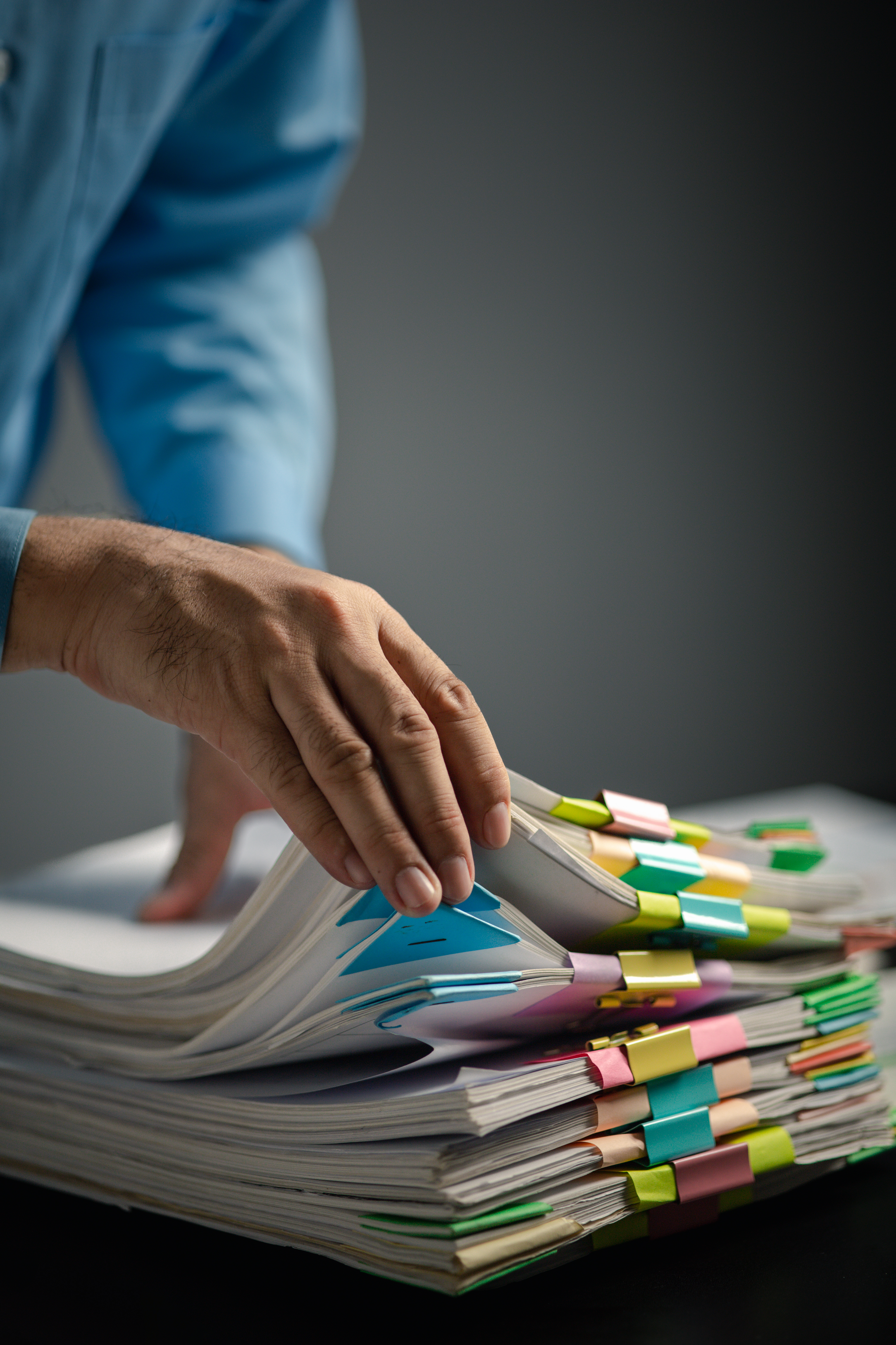 Person with stacks of company financial report papers in office,
